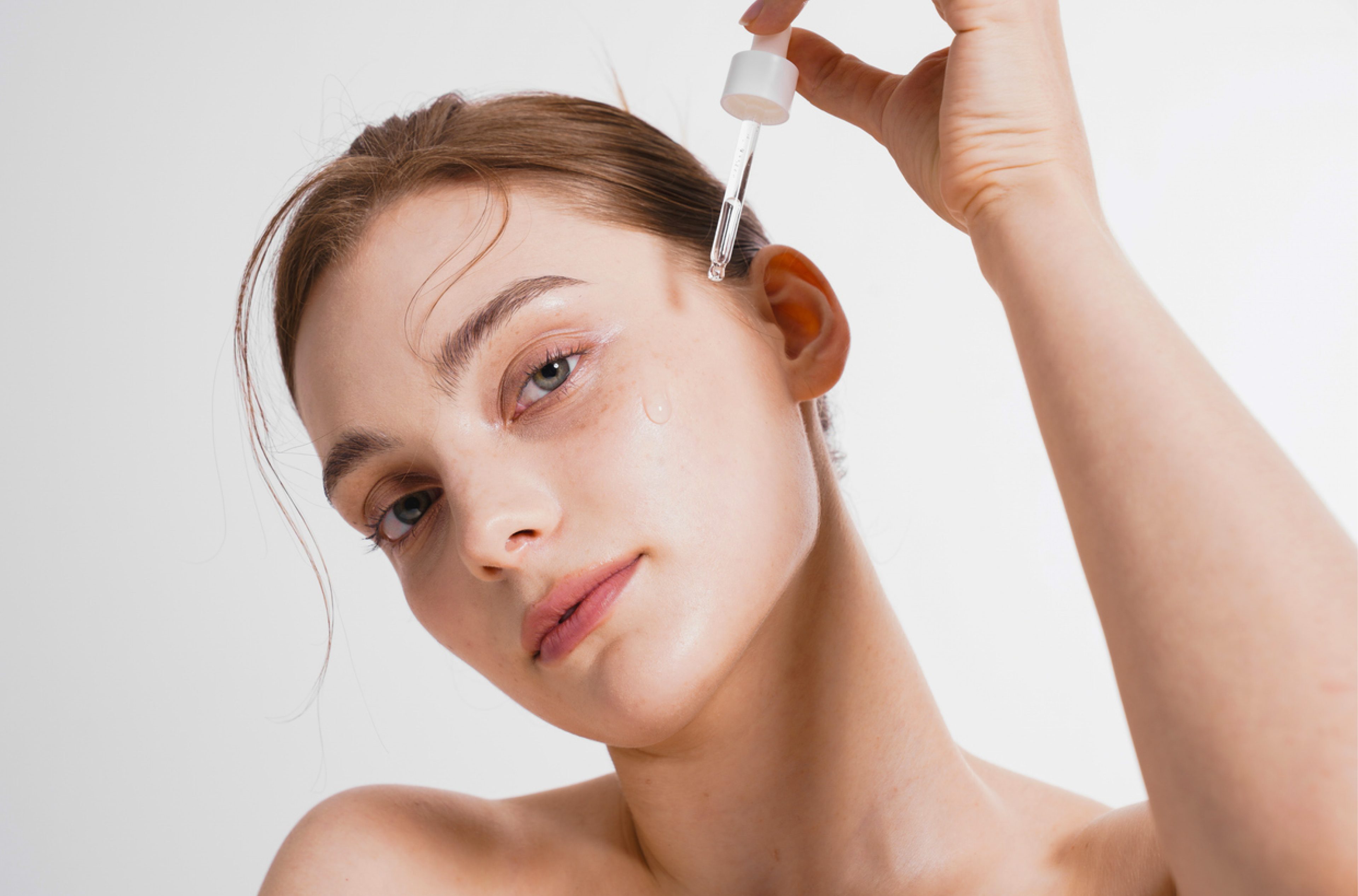 Женщина использует пипетку с сывороткой для ухода за кожей лица после 25 лет