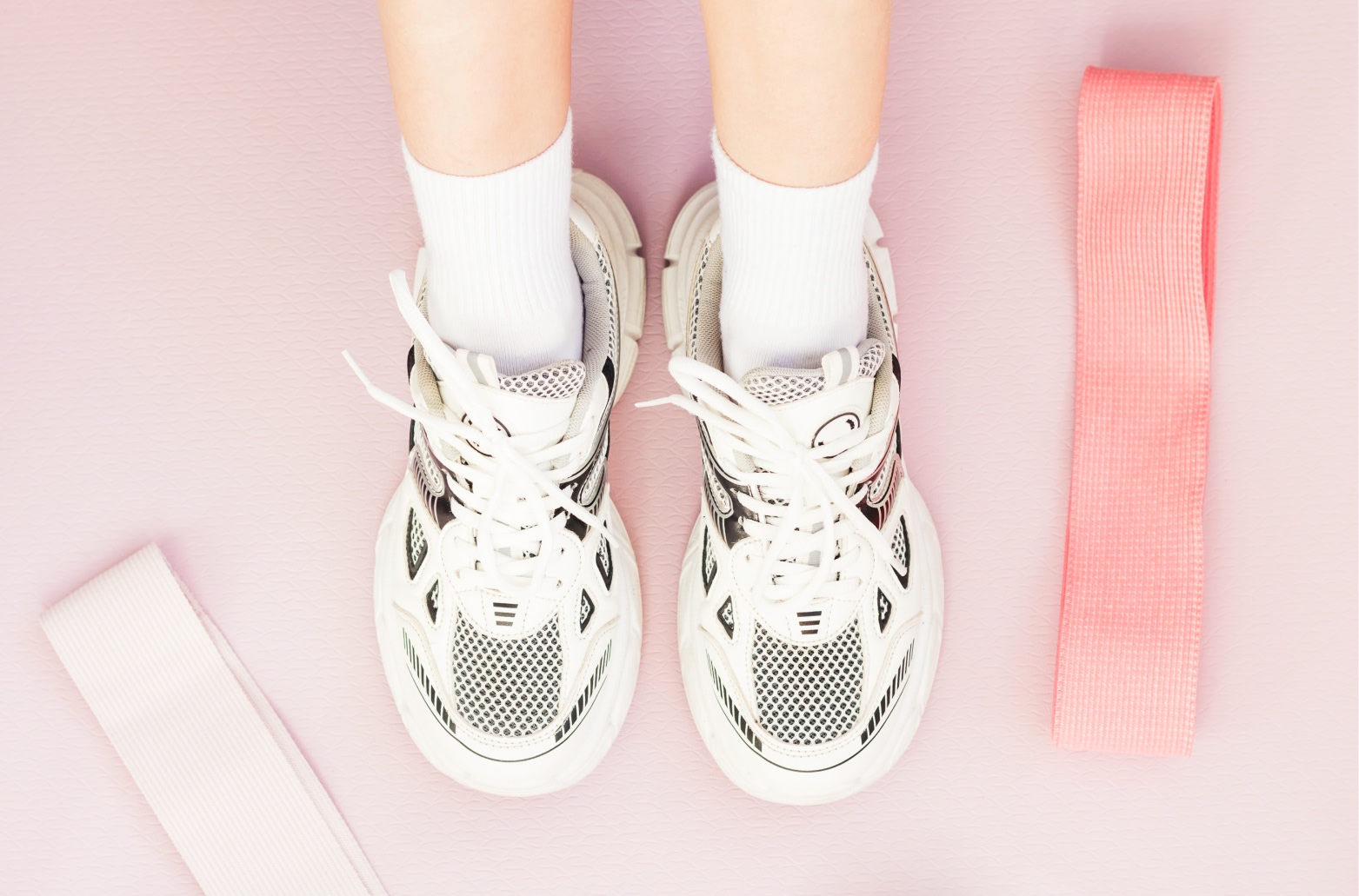 Ноги девушки в кроссовках и спортивные резинки для упражнений на гибкость